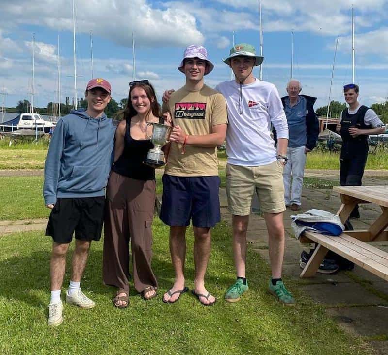 The 2024 winning cuppers team from Caius and Homerton with the Yule-Oldham trophy standing on the grass at Grafham Water