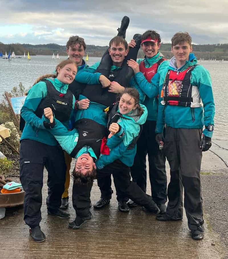 Cambridge blue team by the water with one team member upside down